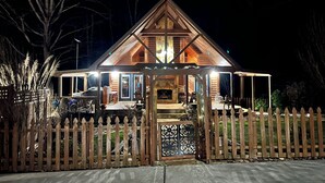 A two-story log cabin with a porch and a picket fence. - The charming cabin (Bowdon)