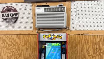 Una màquina recreativa de Pac-Man, un televisor i un cartell penjat a la paret.