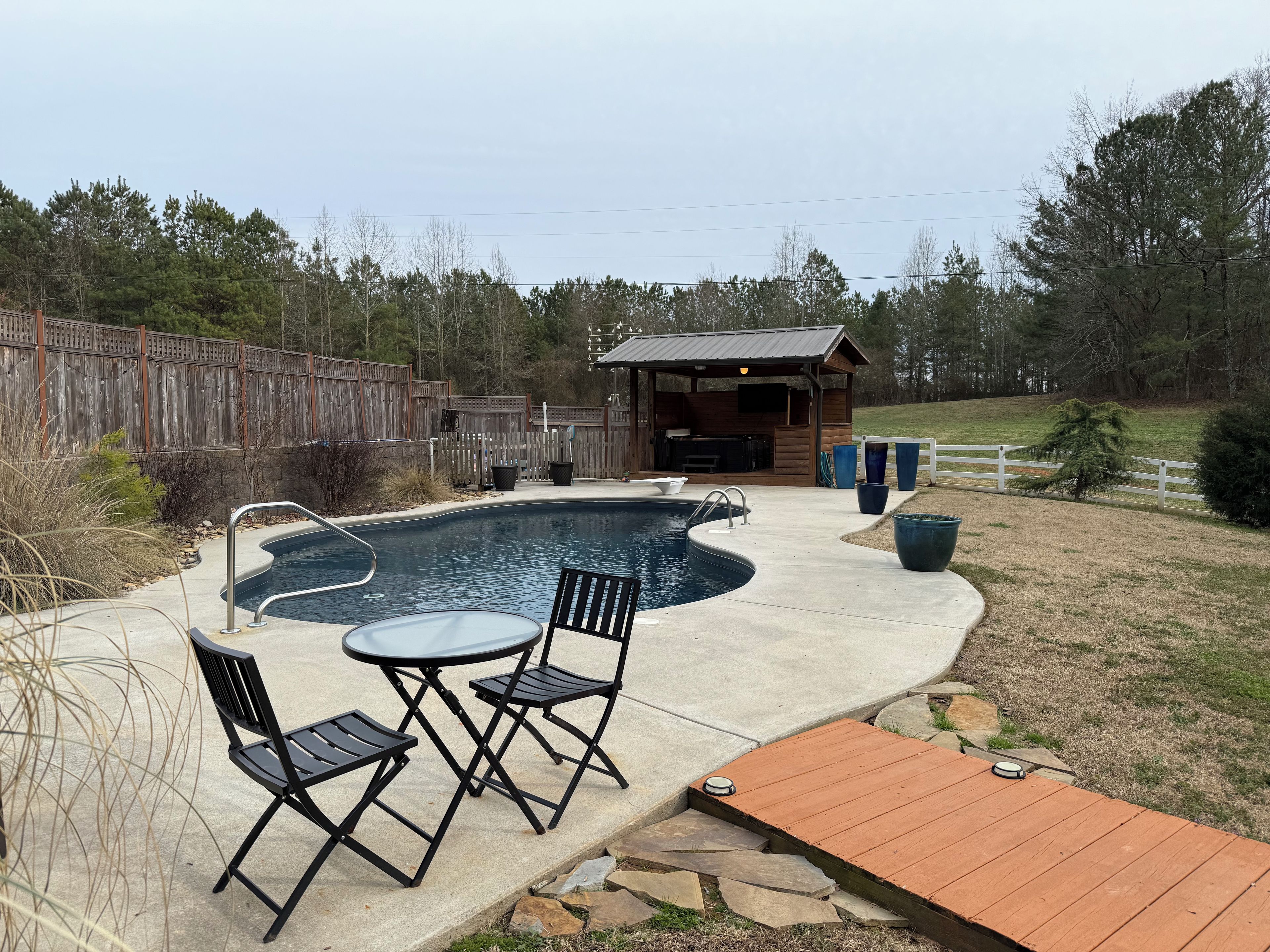 A backyard with a swimming pool, outdoor furniture, and a wooden deck.