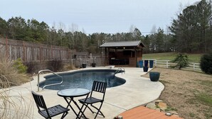 A backyard with a swimming pool, outdoor furniture, and a wooden deck. - The charming cabin (Bowdon)
