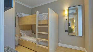 A bunk bed with a ladder, a bedside table, and a wall-mounted lamp.