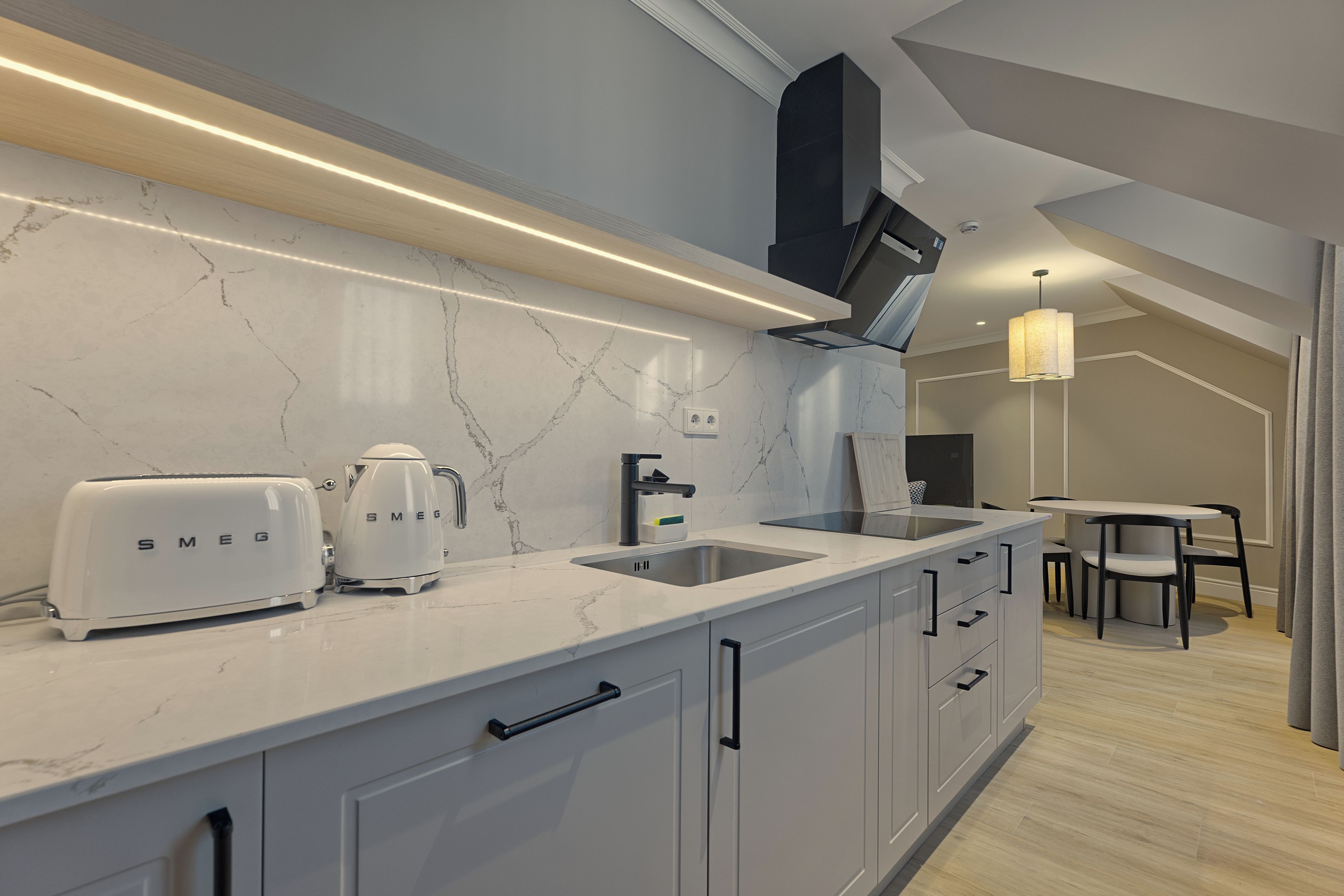 A modern kitchen with a marble countertop, white cabinets, and a built-in oven.