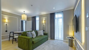 Una sala moderna con un sofá verde, una mesa de comedor y un televisor montado en la pared.