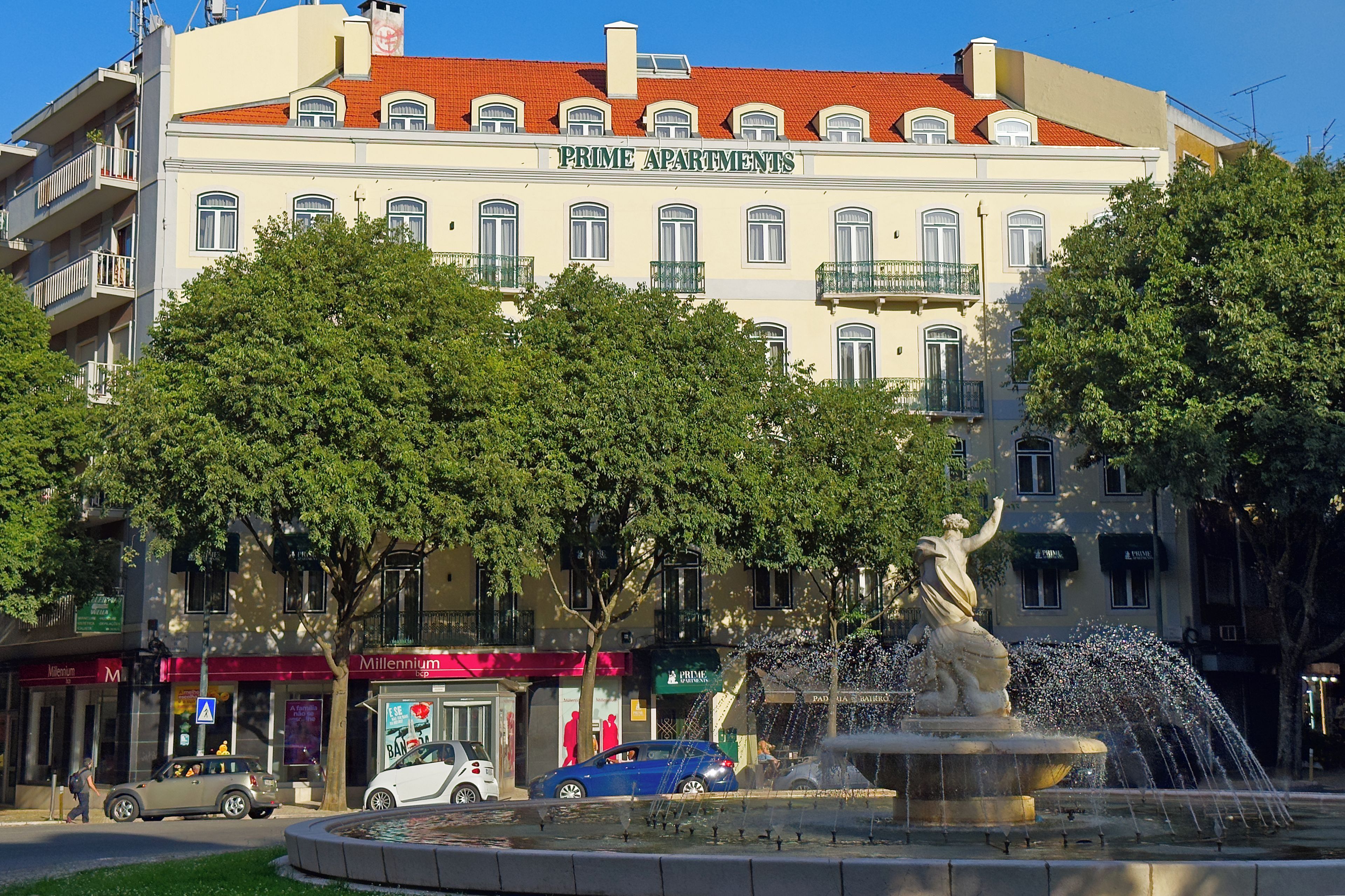 A building with the sign 'Prime Apartments' and a fountain in front.