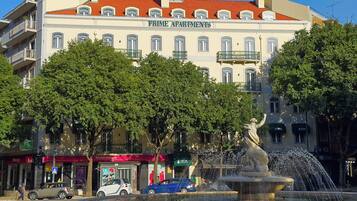 A building with the sign 'Prime Apartments' and a fountain in front.
