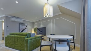 Una sala moderna con un sofá verde, una mesa de comedor redonda y un televisor de pantalla plana.