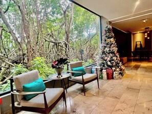 Quarto com duas cadeiras, uma mesinha e um pinheiro de Natal com presentes.