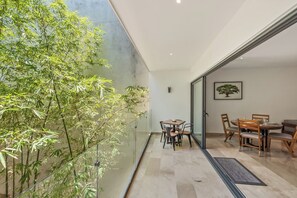 Ein modernes Interieur mit einer Glaswand, einem Essbereich mit Holztischen und einer Bambuspflanze.