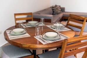 A round wooden dining table set with plates, glasses, and cutlery, surrounded by chairs. - Mamitas Beach & 5 ta street | Pool & Ocean Views (Playa del Carmen)