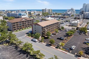 A multi-story hotel with a parking lot, located near a coastal area with buildings and a clear sky. - Jamaica Daybreak North (Ocean City)