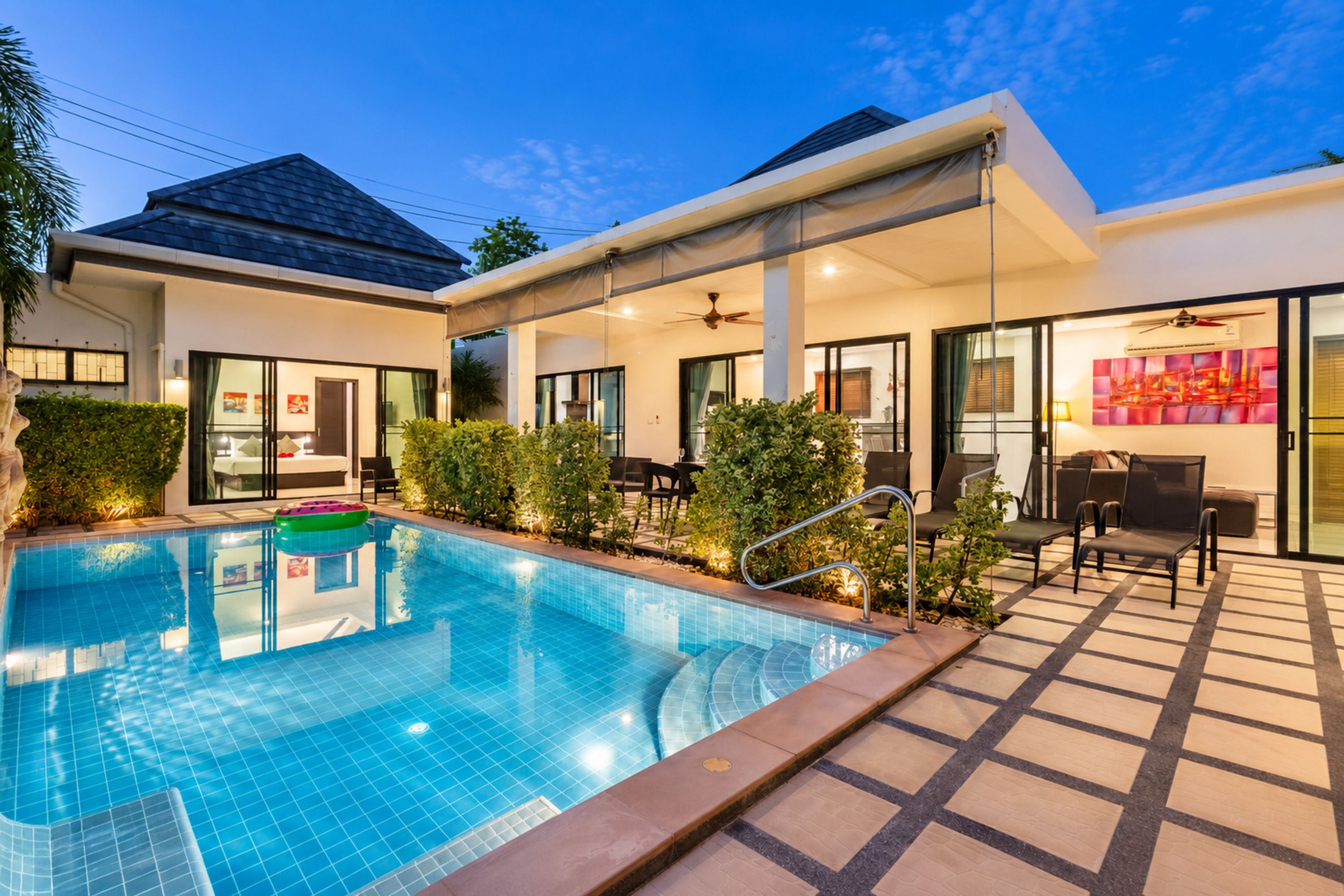 A modern hotel with a swimming pool, outdoor seating area, and a covered patio.