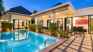 A modern hotel with a swimming pool, outdoor seating area, and a covered patio.