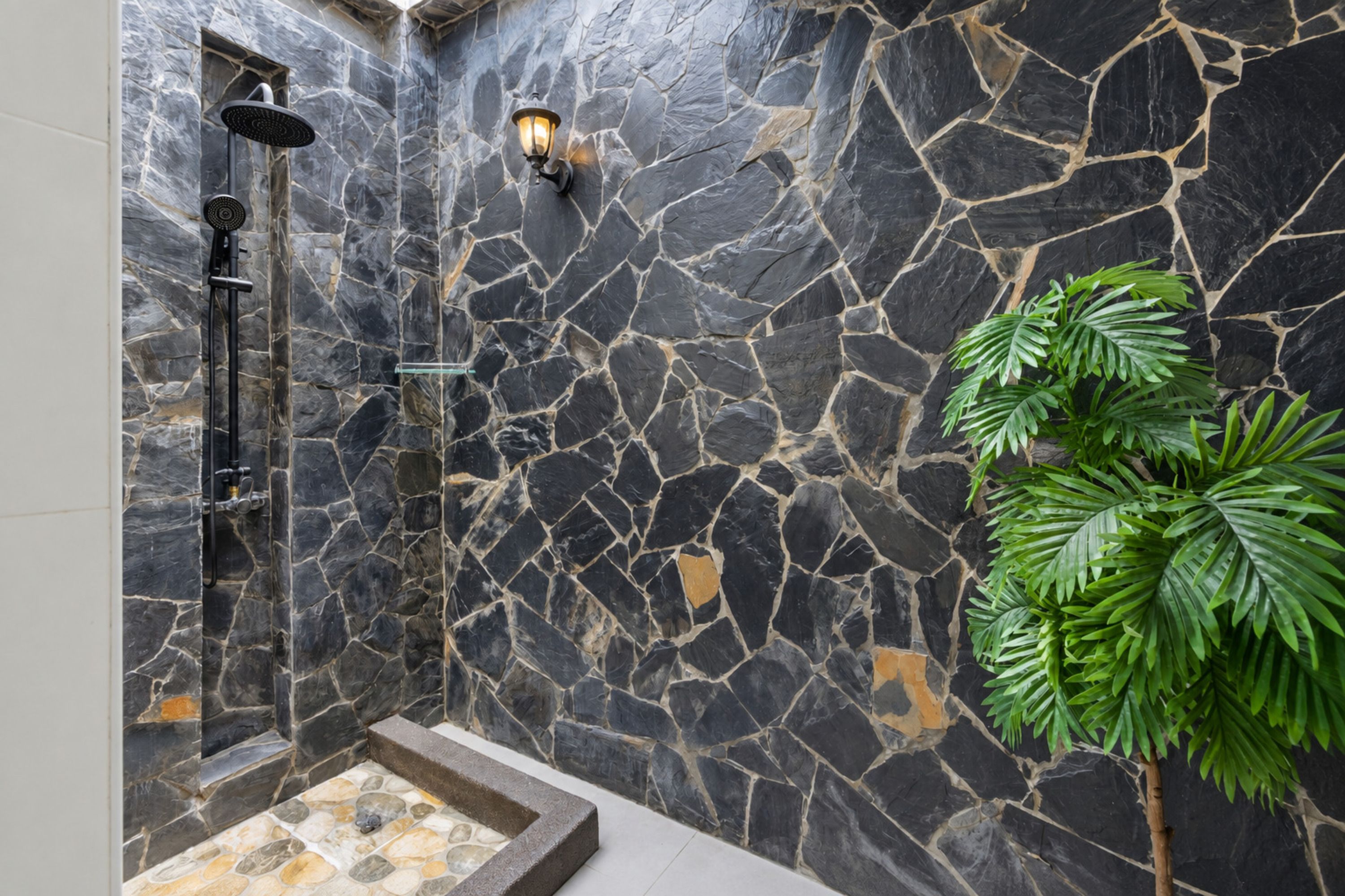 A stone-walled shower area with a built-in bench and a potted plant.