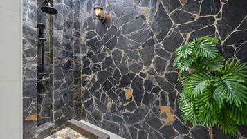 A stone-walled shower area with a built-in bench and a potted plant.