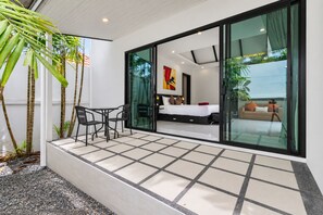 A modern hotel room with a balcony, a bed, a desk, and chairs. - 2 BR Pool Villa Clos Vougeot  (Muang Phuket)