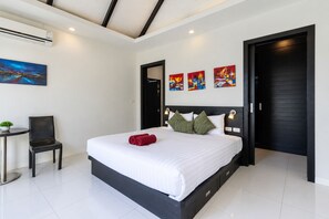 A modern hotel room with a large bed, a desk, and a chair. There are three paintings on the wall, and the room has a black and white color scheme. - 2 BR Pool Villa Clos Vougeot  (Muang Phuket)