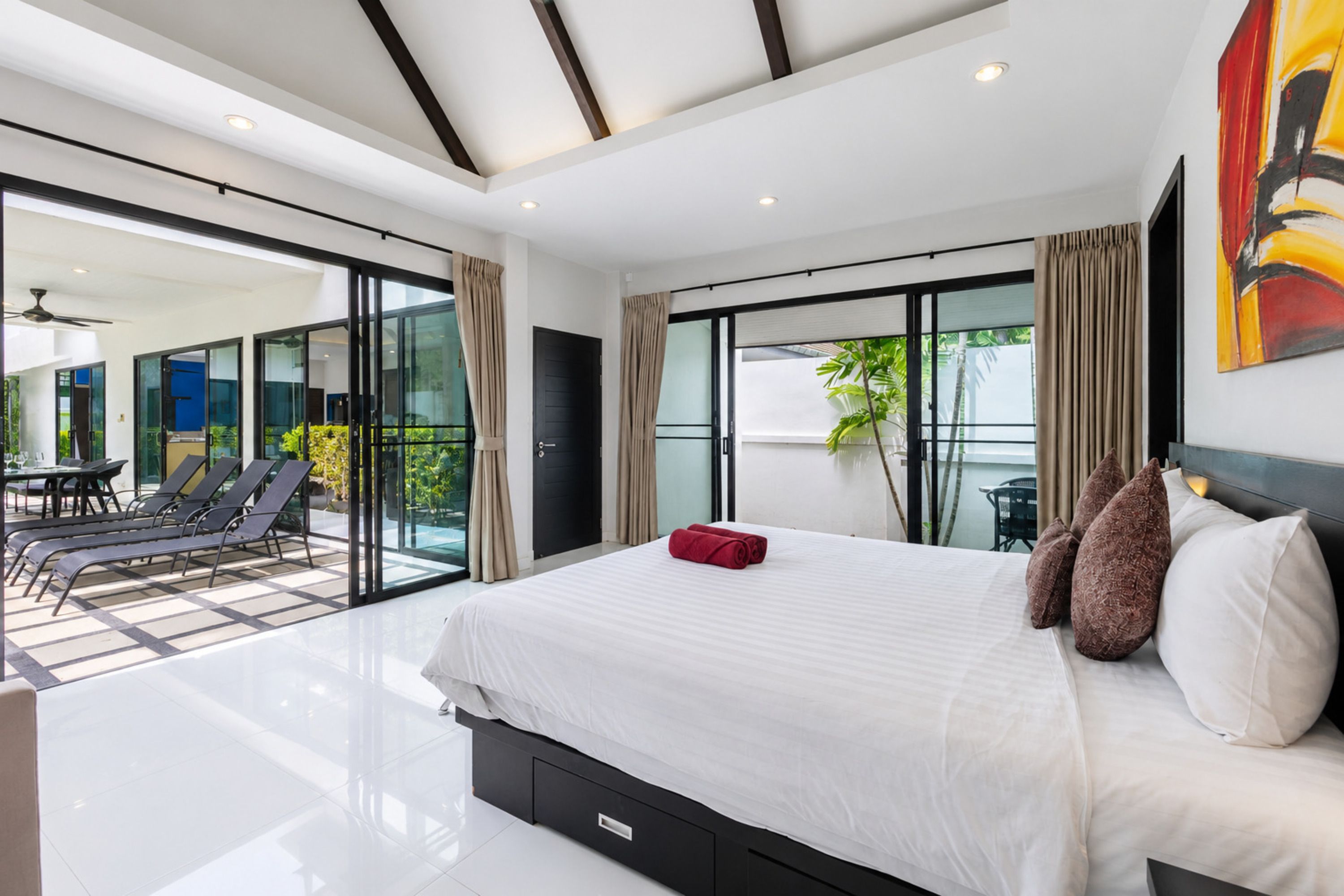 Un dormitorio moderno con una cama grande, un ventanal corredero que da a un balcón y vistas al exterior.