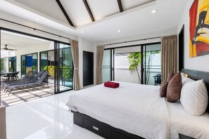 A modern bedroom with a large bed, a sliding glass door leading to a balcony, and a view of the outdoors. - 2 BR Pool Villa Clos Vougeot  (Muang Phuket)