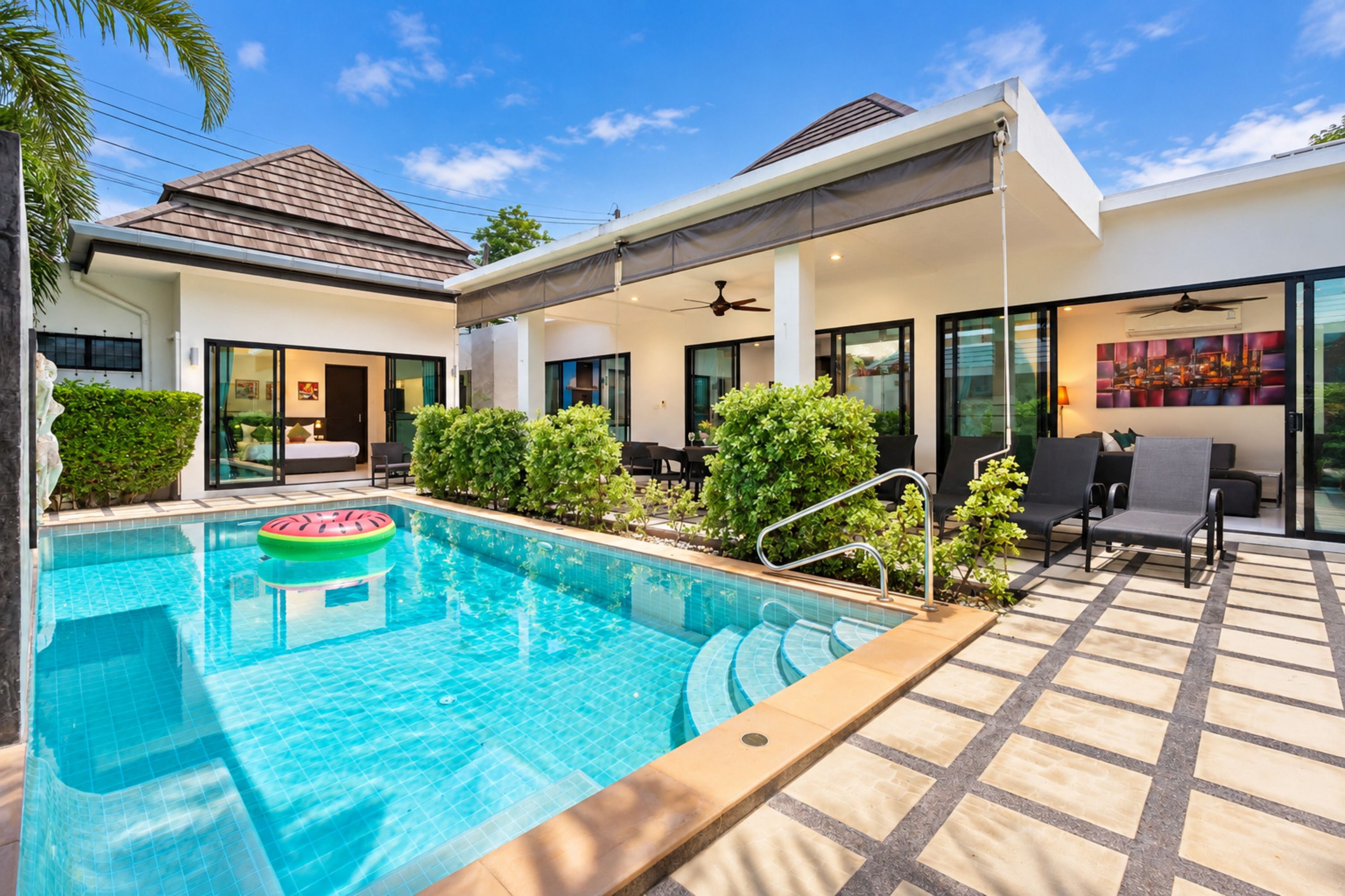 A modern residential property with a swimming pool, outdoor seating area, and a covered patio.