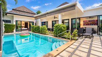 A modern residential property with a swimming pool, outdoor seating area, and a covered patio.