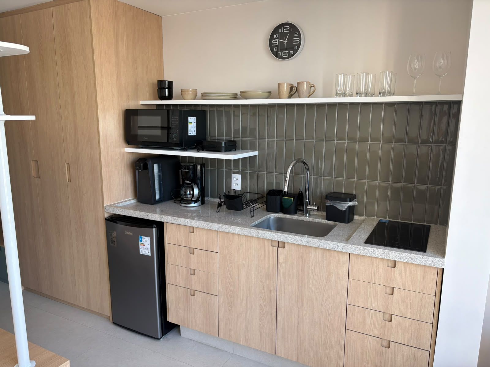 Ett modernt kök med inbyggd diskmaskin, kaffebryggare, mikrovågsugn och diskho.
