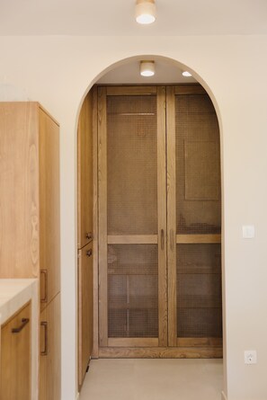 Ein Holzkleiderkasten mit Mesh-Geflecht, ein Holzkabinett zur Linken und eine deckenintegrierte Beleuchtung.