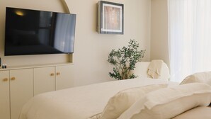 A bedroom with a bed, a television mounted on the wall, a hanging light fixture, and a framed picture. - Casa Casolare by The Residence (Šibenik)