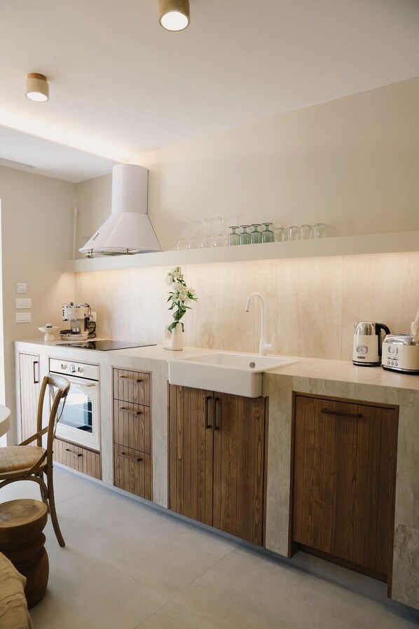 A modern kitchen with a central island, wooden cabinets, a built-in oven, and a range hood.