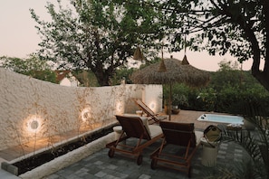 A patio with lounge chairs, a small pool, and a stone wall.