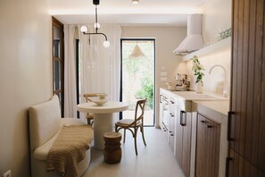 A compact kitchen with a dining area, featuring a round table, chairs, and a built-in stove.