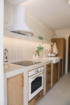 A modern kitchen with a built-in oven, a stainless steel range hood, and wooden cabinetry.