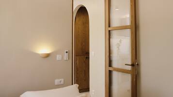Une chambre à coucher comprenant un lit, une armoire en bois, un luminaire fixé au mur et un ventilateur de plafond.