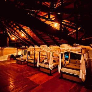 A series of four elevated beds with canopies, wooden beams, and a sloped ceiling.