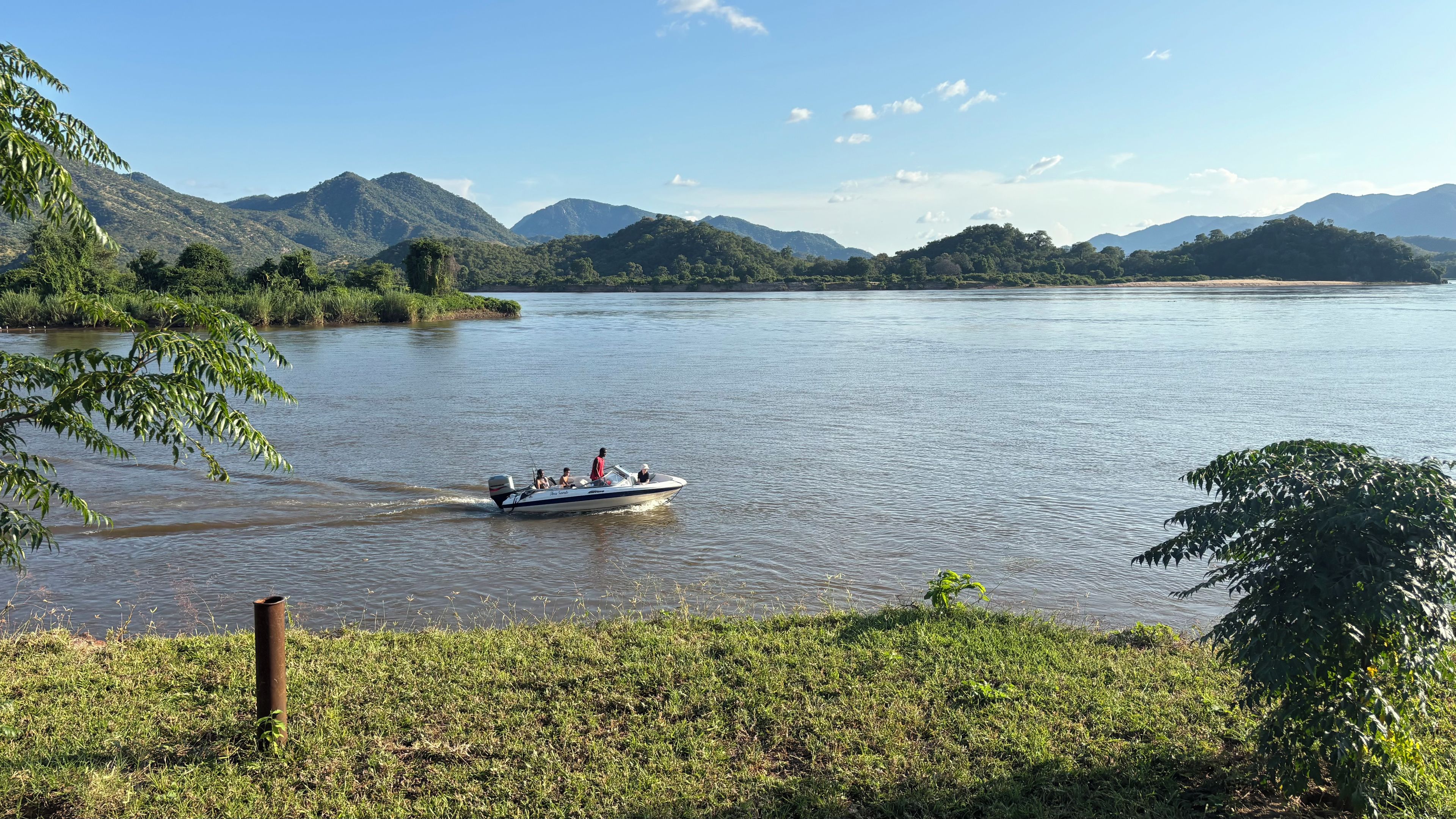 Um barco em um rio calmo, com montanhas ao fundo.