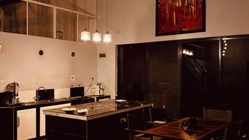 Cozinha moderna com ilha central, iluminação pendente e uma grande pintura na parede.