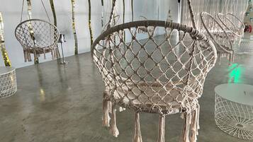 Una stanza con poltrone in macramè, un tavolo rotondo e una sedia sospesa in macramè.