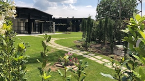 A modern building with a paved courtyard, surrounded by greenery and a clear sky. - ITV CASERTA (San Nicola La Strada)