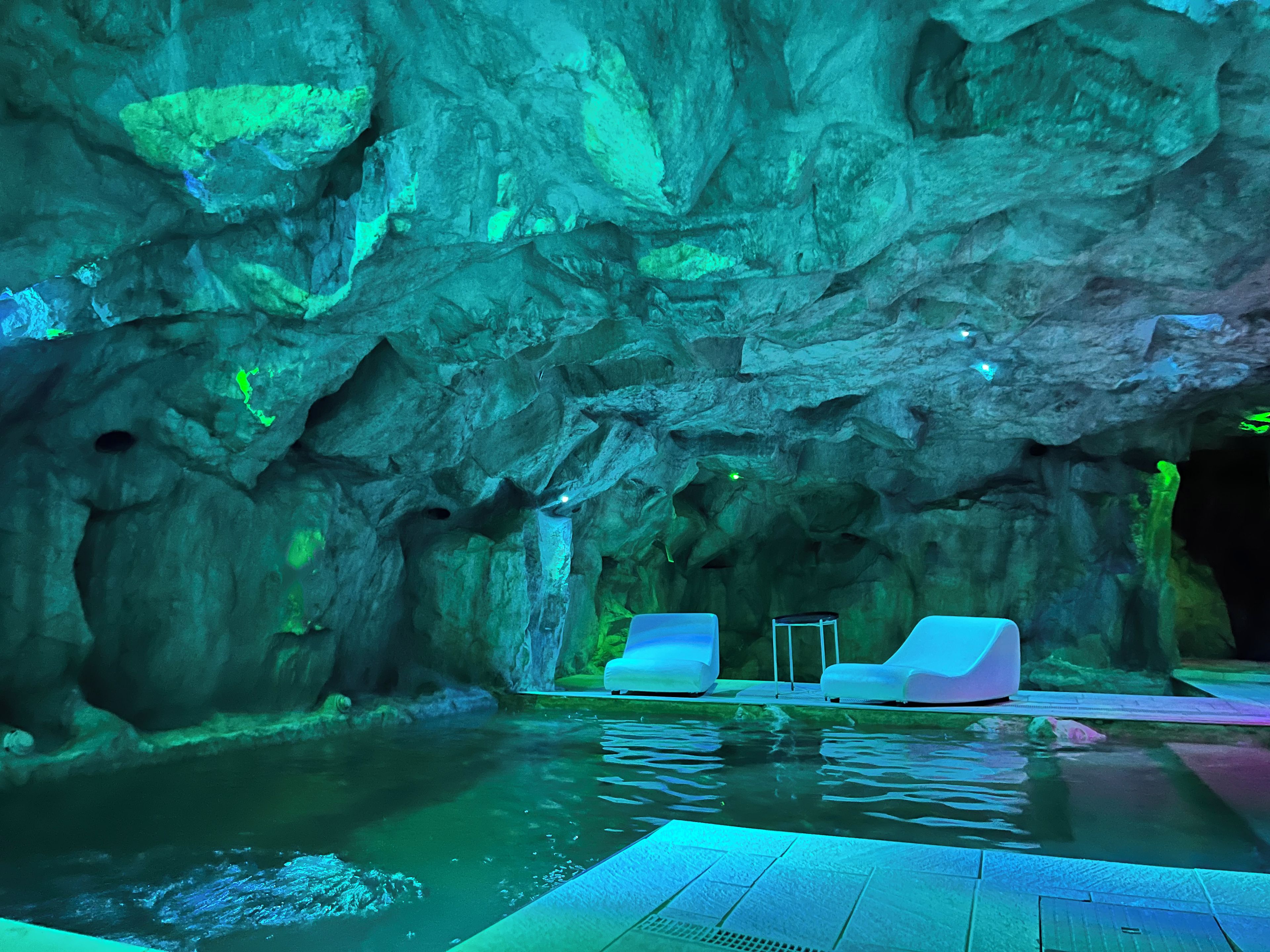 A pool area with rock formations and two lounge chairs.