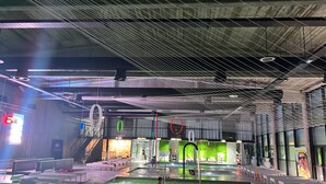 Área de piscina interna com design moderno, incluindo teto com luminárias lineares e escada visível que leva a um andar superior.