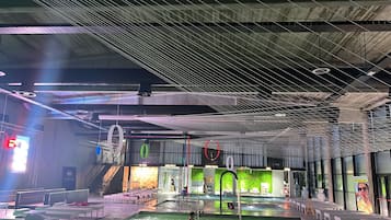 Un espace piscine intérieure au design moderne, comprenant un plafond doté de luminaires linéaires et un escalier apparent menant à un niveau supérieur.