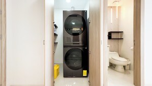 Une petite salle de bain comprenant des toilettes, un lave-linge et une petite étagère.