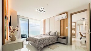 Une chambre moderne avec un grand lit, une table de chevet, une commode, une armoire intégrée et une vue sur la mer.