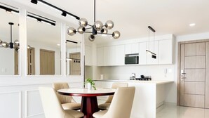 Une cuisine moderne avec des meubles blancs, un îlot central et un coin repas comprenant une table ronde et des chaises.