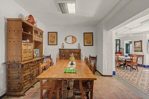 Une salle à manger avec une longue table en bois, des chaises et un buffet orné d’objets décoratifs.