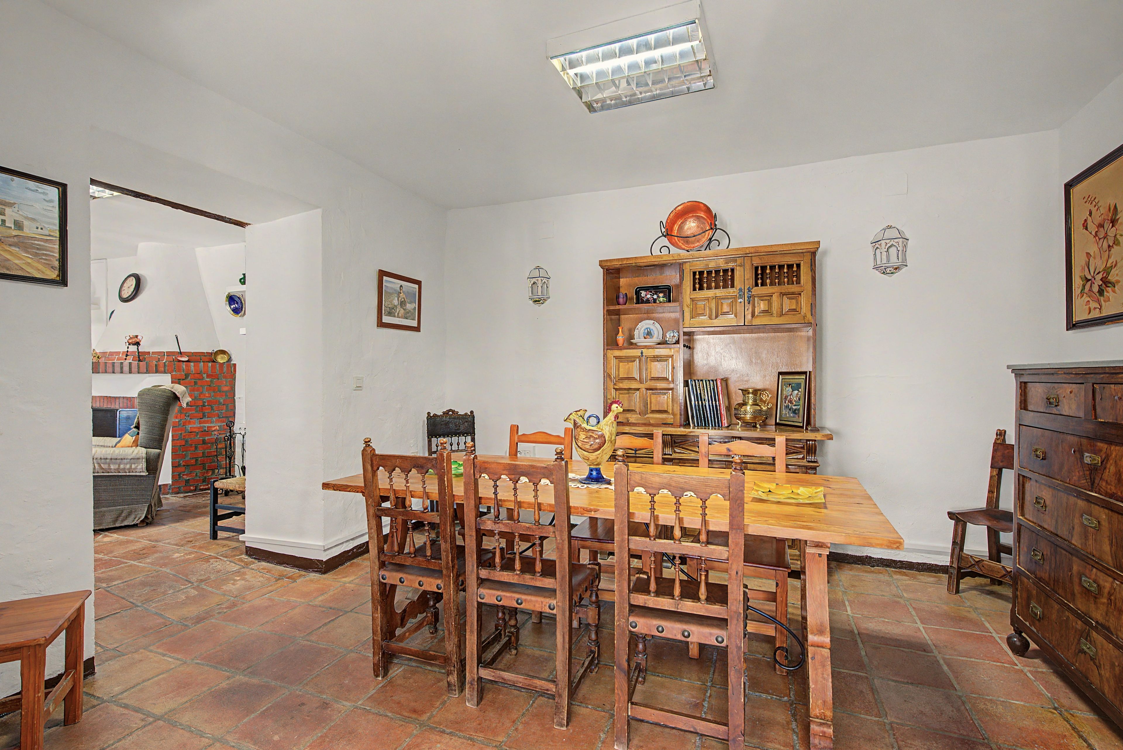 A dining area with a wooden table and chairs, a kitchen area with cabinets and a stove, and a tiled floor.