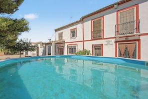 Un edificio con piscina, varias ventanas con rejas y un letrero que dice 'CASERIA LAS MARAVILLAS'.