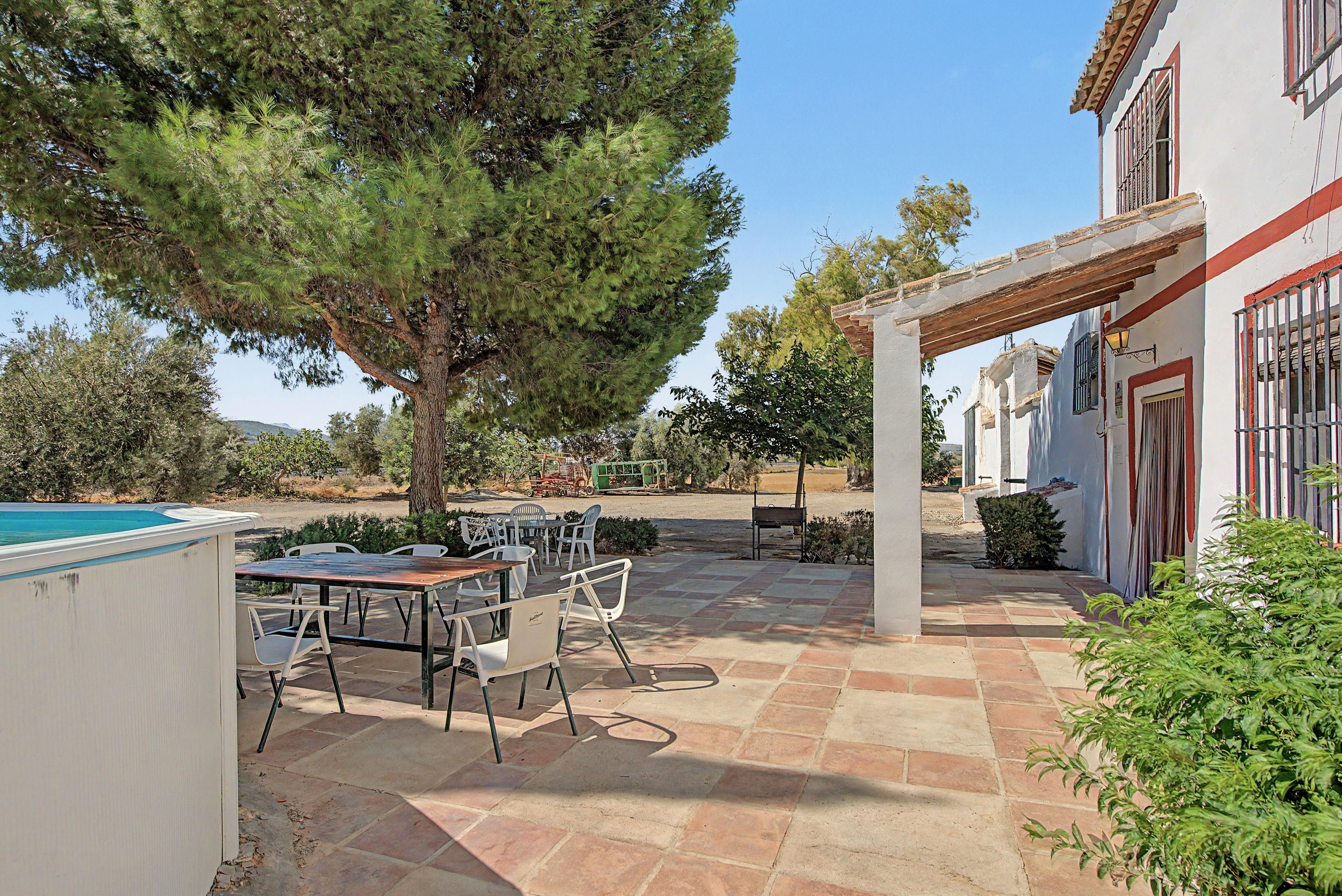Une terrasse extérieure avec une piscine, un coin repas et une pergola.