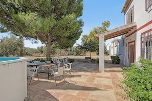 Une terrasse extérieure avec une piscine, un coin repas et une pergola.
