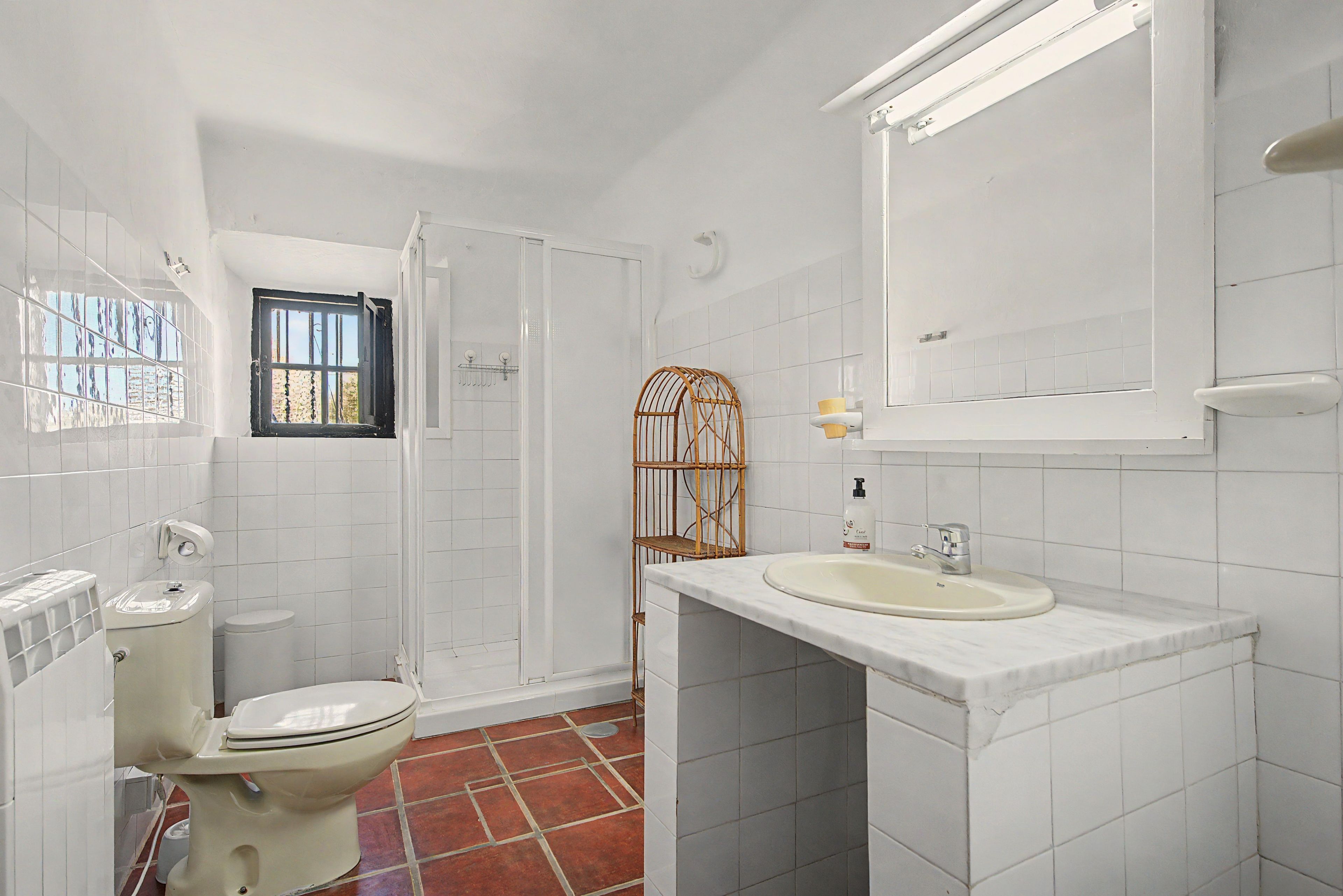 A bathroom with a toilet, a shower, a sink, and a mirror.