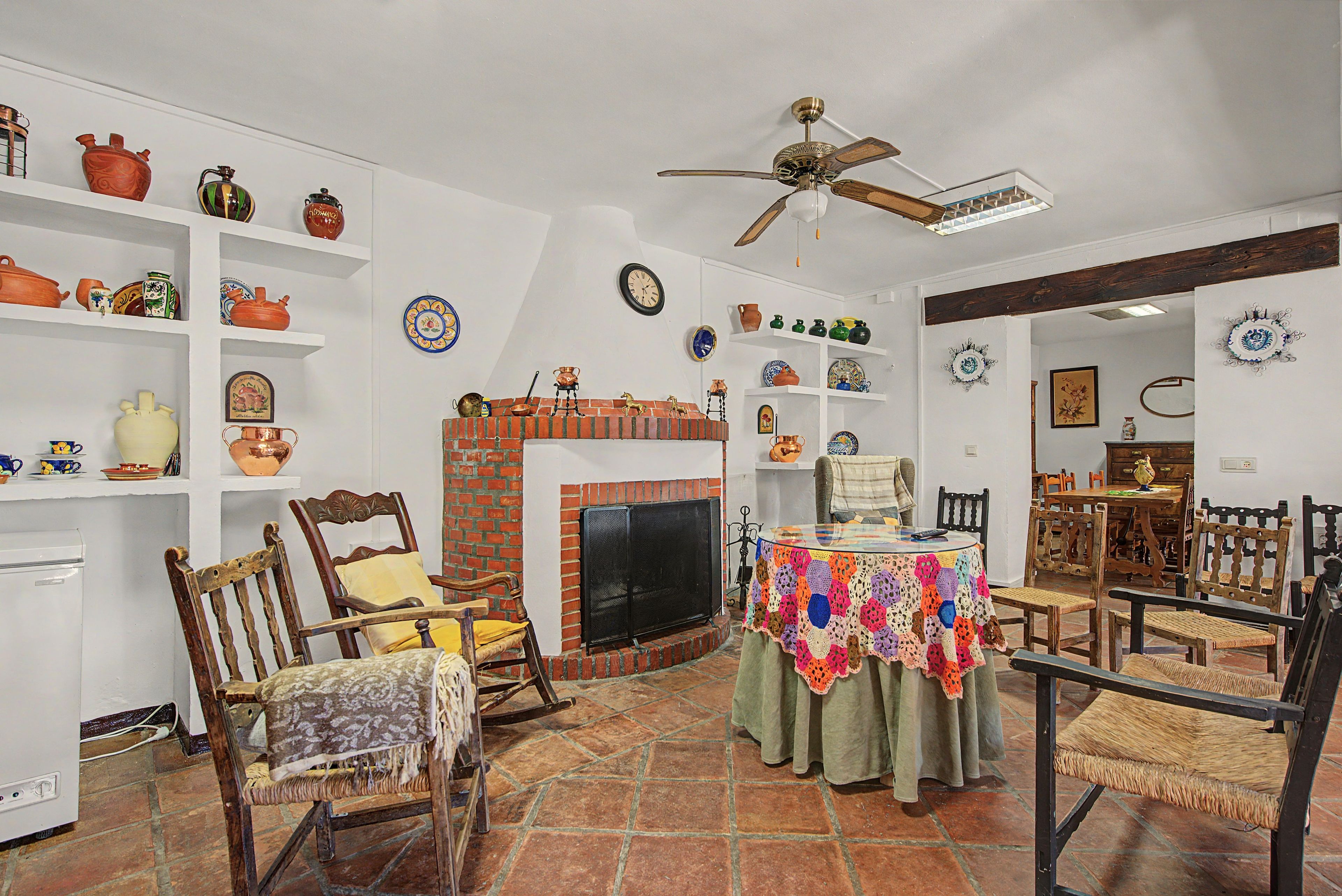 A traditional living room with a fireplace, wooden furniture, and decorative plates on shelves.